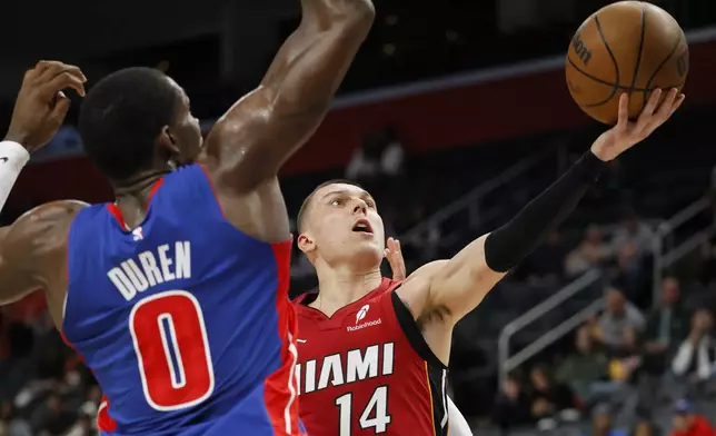 Miami Heat guard Tyler Herro (14) goes to the basket past Detroit Pistons center Jalen Duren (0) during the first half of an NBA basketball game Monday, Dec. 16, 2024, in Detroit. (AP Photo/Duane Burleson)