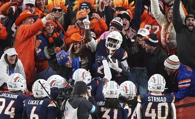 Denver Broncos cornerback Ja'Quan McMillian, center, celebrates with fans after returning an interception for a touchdown in the second half of an NFL football game against the Cleveland Browns, Monday, Dec. 2, 2024, in Denver. (AP Photo/David Zalubowski)