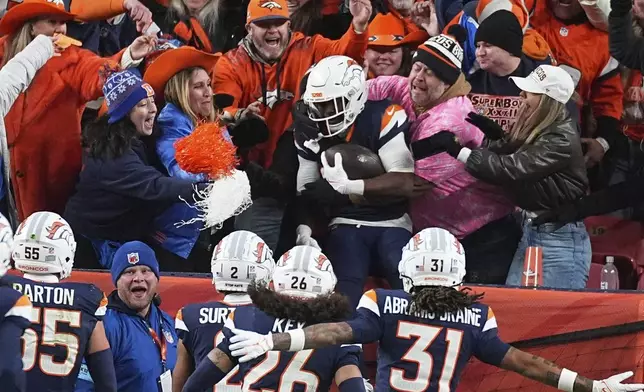 Denver Broncos cornerback Ja'Quan McMillian, back center, is congratulated by fans after returning an interception for a touchdown in the second half of an NFL football game against the Cleveland Browns, Monday, Dec. 2, 2024, in Denver. (AP Photo/David Zalubowski)