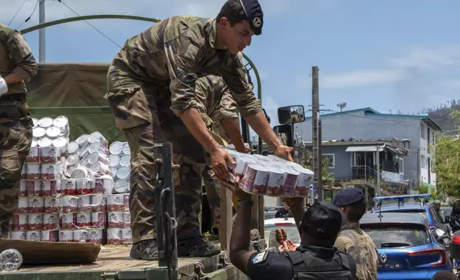 This photo provided by the French Army shows a soldier unloading cans of food in the Indian Ocean French territory of Mayotte, Wednesday Dec.18, 2024, as the cyclone on Saturday was the deadliest storm to strike the territory in nearly a century. (D Piatacrrea, Etat Major des Armees/Legion Etrangere via AP)