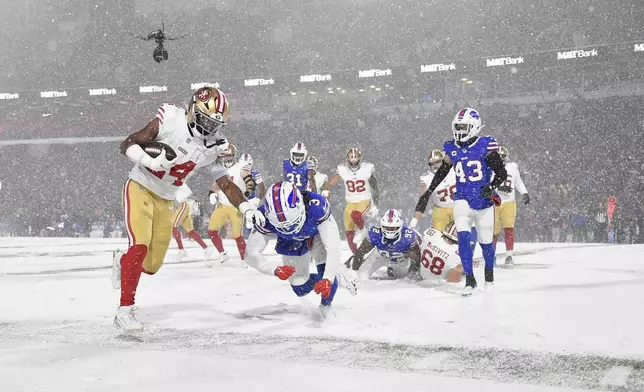 San Francisco 49ers running back Jordan Mason (24) runs against Buffalo Bills safety Damar Hamlin (3) during the second half of an NFL football game in Orchard Park, N.Y., Sunday, Dec. 1, 2024. (AP Photo/Adrian Kraus)