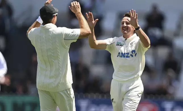 New Zealand's Nathan Smith, right, is congratulated by teammate Tim Southee after taking the wicket of England's Joe Root during play on day one of the second cricket test between New Zealand and England at the Basin Reserve in Wellington, New Zealand, Friday, Dec.6, 2024. (Andrew Cornaga/Photosport via AP)