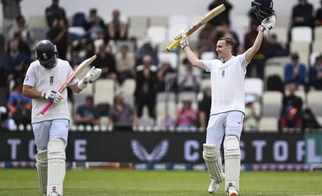 England's Harry Brook, right, celebrates after scoring a century as teammate Ollie Pope reacts during play on day one of the second cricket test between New Zealand and England at the Basin Reserve in Wellington, New Zealand, Friday, Dec.6, 2024. (Andrew Cornaga/Photosport via AP)