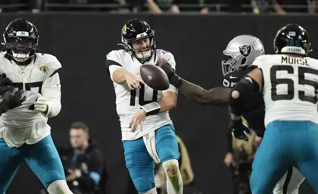 Jacksonville Jaguars quarterback Mac Jones, center, is forced to throw the ball away as he is pressured by Las Vegas Raiders defensive tackle John Jenkins, second from right, as Jaguars center Mitch Morse (65) and Jaguars offensive tackle Anton Harrison, left, try to make blocks during the second half of an NFL football game Sunday, Dec. 22, 2024, in Las Vegas. (AP Photo/John Locher)