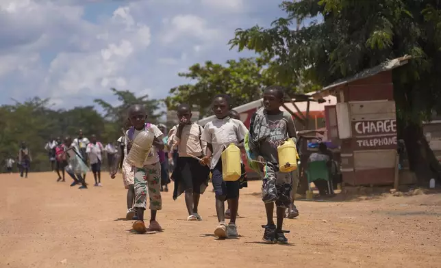 Children walk and play music on plastic jugs at the Epulu village in the Okapi Wildlife Reserve in Congo, Sept. 21, 2024. (AP Photo/Sam Mednick)