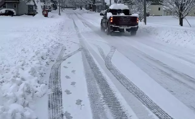 A vehicle drives on a snowy street in Lowville, N.Y., on Saturday, Nov. 30, 2024. (AP Photo/Cara Anna)