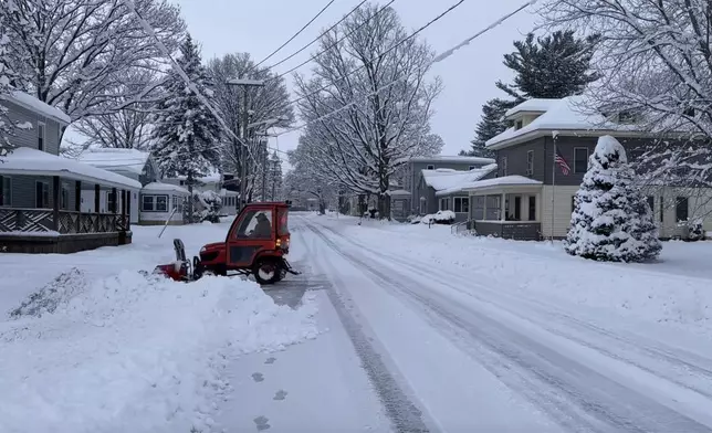 A person clears the snow from the sidewalk in Lowville, N.Y., on Saturday, Nov. 30, 2024. (AP Photo/Cara Anna)