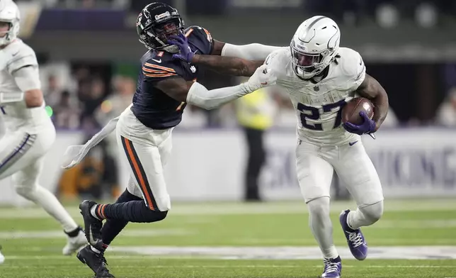 Minnesota Vikings running back Cam Akers (27) tries to break a tackle by Chicago Bears cornerback Jaylon Johnson (1) during the second half of an NFL football game, Monday, Dec. 16, 2024, in Minneapolis. (AP Photo/Abbie Parr)