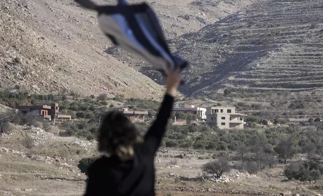 Salma Safadi waves a shirt to her sister Sawsan Safadi, who lives inside the buffer zone near the so-called Alpha Line that separates the Israeli-controlled Golan Heights from Syria, in the town of Majdal Shams, Tuesday, Dec. 17, 2024. (AP Photo/Matias Delacroix)