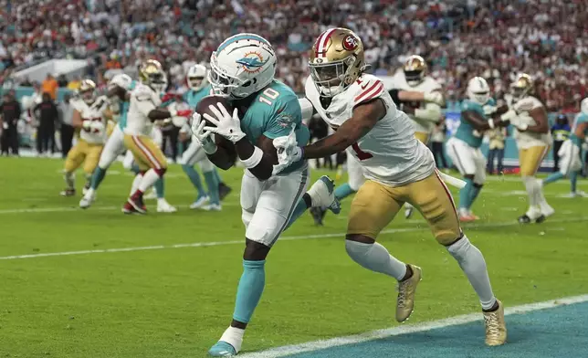 Miami Dolphins wide receiver Tyreek Hill (10) catches a pass for a touchdown as San Francisco 49ers cornerback Charvarius Ward (7) gives him a push during the first half of an NFL football game, Sunday, Dec. 22, 2024, in Miami Gardens, Fla. (AP Photo/Rebecca Blackwell)