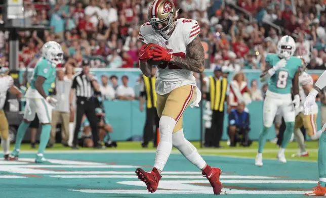 San Francisco 49ers tight end Eric Saubert (82) catches a pass for a touchdown during the second half of an NFL football game against the Miami Dolphins, Sunday, Dec. 22, 2024, in Miami Gardens, Fla. (AP Photo/Rebecca Blackwell)