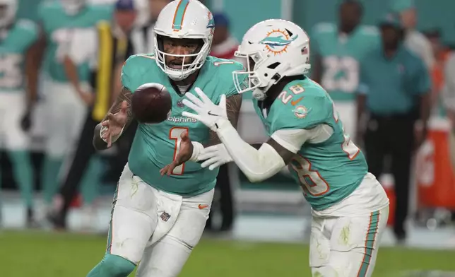 Miami Dolphins quarterback Tua Tagovailoa (1) pitches the football to Miami Dolphins running back De'Von Achane (28) during the second half of an NFL football game against the San Francisco 49ers, Sunday, Dec. 22, 2024, in Miami Gardens, Fla. (AP Photo/Lynne Sladky)