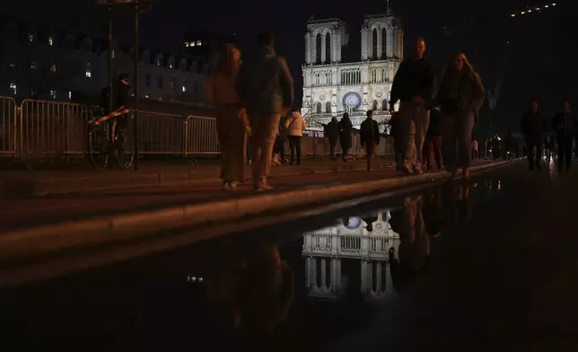 Notre Dame cathedral is reflected in a puddle in Paris, Friday, Dec. 6, 2024. (AP Photo/Alessandra Tarantino)