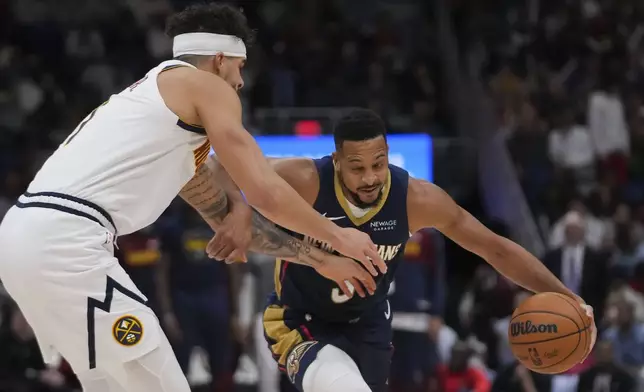 New Orleans Pelicans guard CJ McCollum drives to the lane against Denver Nuggets forward Michael Porter Jr. in the first half of an NBA basketball game in New Orleans, Sunday, Dec. 22, 2024. (AP Photo/Gerald Herbert)