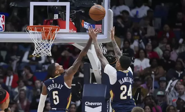 New Orleans Pelicans guard Dejounte Murray (5) and New Orleans Pelicans guard Jordan Hawkins (24) leap for a rebound in the first half of an NBA basketball game in New Orleans, Sunday, Dec. 22, 2024. (AP Photo/Gerald Herbert)