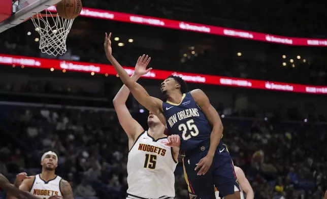 New Orleans Pelicans guard Trey Murphy III (25) goes to the basket over Denver Nuggets center Nikola Jokic (15) in the first half of an NBA basketball game in New Orleans, Sunday, Dec. 22, 2024. (AP Photo/Gerald Herbert)