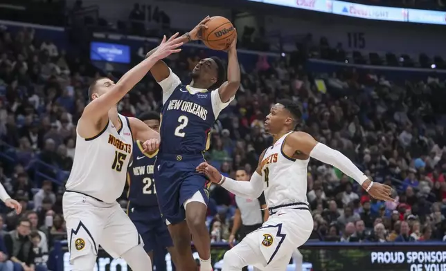 New Orleans Pelicans forward Herbert Jones (2) goes to the basket between Denver Nuggets center Nikola Jokic (15) and guard Russell Westbrook (4) in the first half of an NBA basketball game in New Orleans, Sunday, Dec. 22, 2024. (AP Photo/Gerald Herbert)