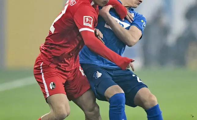 Freiburg's Ritsu Doan, left, and Hoffenheim's Alexander Prass fight for the ball during the German Bundesliga soccer match between TSG 1899 Hoffenheim and SC Freiburg at the PreZero Arena, in Sinsheim, Germany, Sunday, Dec. 8, 2024. (Uwe Anspach/dpa via AP)