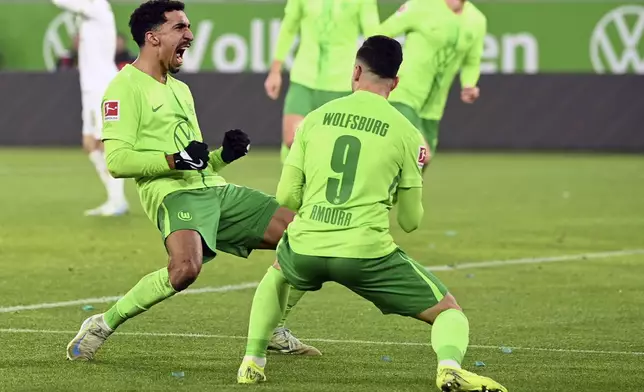 Wolfsburg's Tiago Tomas, left, celebrates scoring his side's second goal during the German Bundesliga soccer match between VfL Wolfsburg and FSV Mainz 05 at the Volkswagen Arena, in Wolfsburg, Germany, Sunday, Dec. 8, 2024. (Swen Pförtner/dpa via AP)