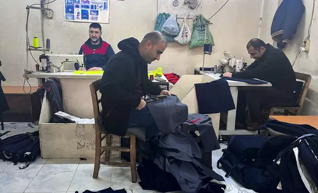 Syrian Mahmut Cabuli, left, works in a textile workshop in Gaziantep, southern Turkey, on Friday, Dec. 13, 2024. (AP Photo/Mehmet Guzel)