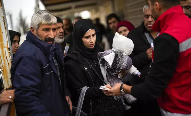 FILE - An officer checks the papers of a Syrian woman before she crosses into Syria from Turkey, at the Oncupinar border gate, near the town of Kilis, southern Turkey, Wednesday, Dec. 11, 2024. (AP Photo/Khalil Hamra, File)