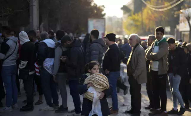 FILE - Residents stand in line to buy bread from a bakery in Aleppo, Syria, on Saturday, Dec. 14, 2024. (AP Photo/Khalil Hamra, File)