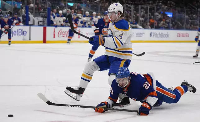 New York Islanders' Kyle Palmieri (21) fights for control of the puck with Buffalo Sabres' Bowen Byram (4) during the second period of an NHL hockey game Monday, Dec. 23, 2024, in Elmont, N.Y. (AP Photo/Frank Franklin II)