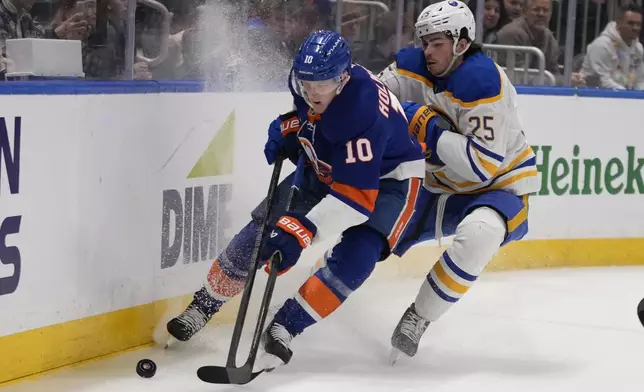 Buffalo Sabres' Owen Power (25) fights for control of the puck with New York Islanders' Simon Holmstrom (10) during the second period of an NHL hockey game Monday, Dec. 23, 2024, in Elmont, N.Y. (AP Photo/Frank Franklin II)