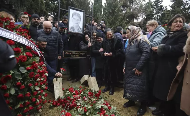 People mourn at the grave of flight attendant Hokume Aliyeva during a funeral of the crew members of the Azerbaijan Airlines Embraer 190 killed in a deadly plane crash in Kazakhstan this week, at the II Alley of Honor in Baku, Azerbaijan, Sunday, Dec. 29, 2024. (AP photo)