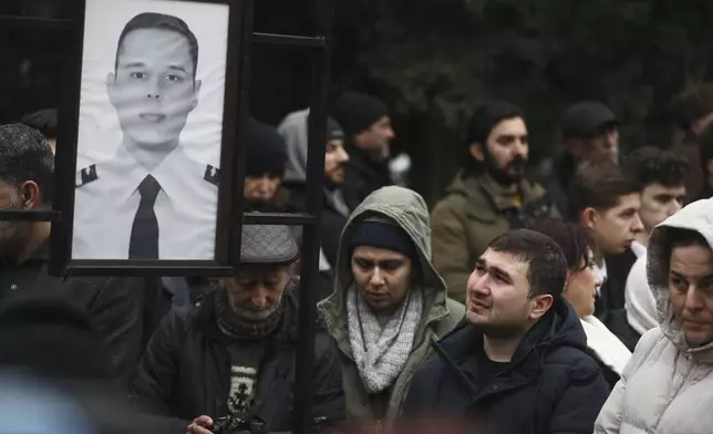 People mourn at the grave of First Officer Aleksandr Kalyaninov during a funeral of the crew members of the Azerbaijan Airlines Embraer 190 killed in a deadly plane crash in Kazakhstan this week, at the II Alley of Honor in Baku, Azerbaijan, Sunday, Dec. 29, 2024. (AP photo)