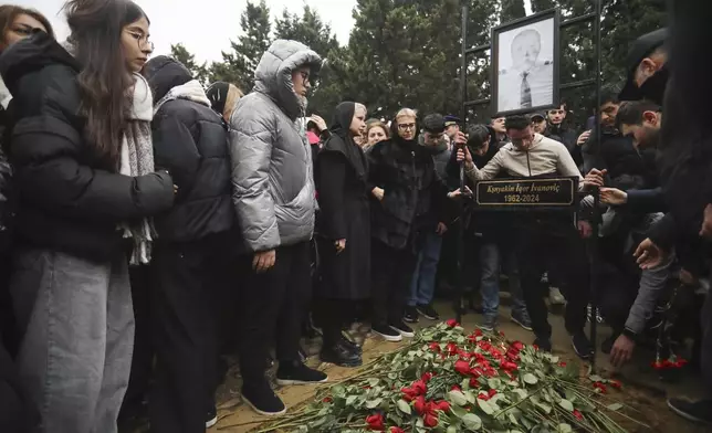 People stand at the grave of pilot in command Igor Kshnyakin during a funeral of the crew members of the Azerbaijan Airlines Embraer 190 killed in a deadly plane crash in Kazakhstan this week, at the II Alley of Honor in Baku, Azerbaijan, Sunday, Dec. 29, 2024. (AP photo)