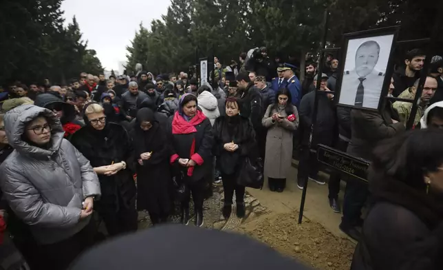 People stand at the grave of pilot in command Igor Kshnyakin during a funeral of the crew members of the Azerbaijan Airlines Embraer 190, killed in a deadly plane crash in Kazakhstan this week, at the II Alley of Honor in Baku, Azerbaijan, Sunday, Dec. 29, 2024. (AP photo)