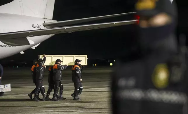 Workers carry a coffin with a body of a victim from a plane after the Azerbaijani Airlines crashed, near the Kazakhstani city of Aktau, upon their arrival at the Heydar Aliyev International Airport outside Baku, Azerbaijan, on Saturday, Dec. 28, 2024. (AP Photo)