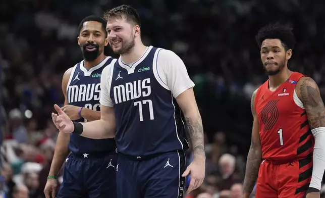 Dallas Mavericks guard Luka Doncic (77) shares a laugh with guard Spencer Dinwiddie (26) as Portland Trail Blazers guard Anfernee Simons (1) looks on during the second half of an NBA basketball game Monday, Dec. 23, 2024, in Dallas. (AP Photo/LM Otero)