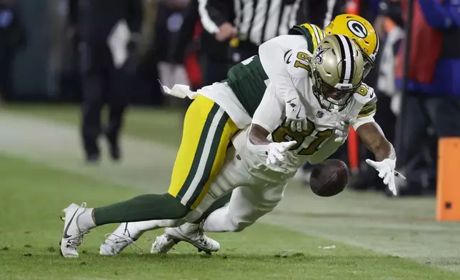 New Orleans Saints wide receiver Kevin Austin Jr. (81) drops the ball as he is hit by Green Bay Packers cornerback Carrington Valentine during the first half of an NFL football game, Monday, Dec. 23, 2024, in Green Bay, Wis. (AP Photo/Matt Ludtke)