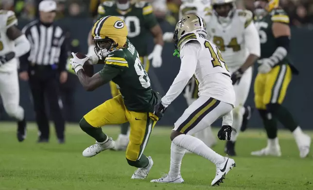 Green Bay Packers wide receiver Romeo Doubs (87) carries on a first down reception against New Orleans Saints cornerback Kool-Aid McKinstry (14) during the first half of an NFL football game, Monday, Dec. 23, 2024, in Green Bay, Wis. (AP Photo/Matt Ludtke)