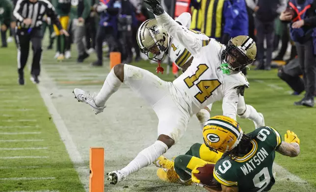 Green Bay Packers wide receiver Christian Watson (9) is knocked out of bounds by New Orleans Saints cornerback Kool-Aid McKinstry (14) during the first half of an NFL football game, Monday, Dec. 23, 2024, in Green Bay, Wis. (AP Photo/Mike Roemer)