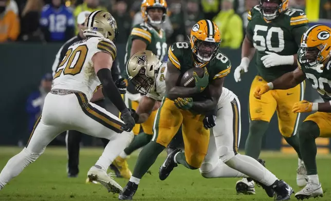 Green Bay Packers running back Josh Jacobs (8) carries against New Orleans Saints linebacker Pete Werner (20) during the first half of an NFL football game, Monday, Dec. 23, 2024, in Green Bay, Wis. (AP Photo/Morry Gash)