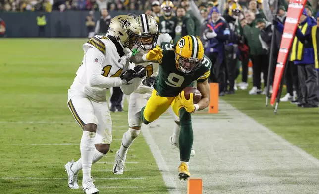 Green Bay Packers wide receiver Christian Watson (9) carries against New Orleans Saints cornerback Alontae Taylor (1) and cornerback Kool-Aid McKinstry (14) during the first half of an NFL football game, Monday, Dec. 23, 2024, in Green Bay, Wis. (AP Photo/Mike Roemer)