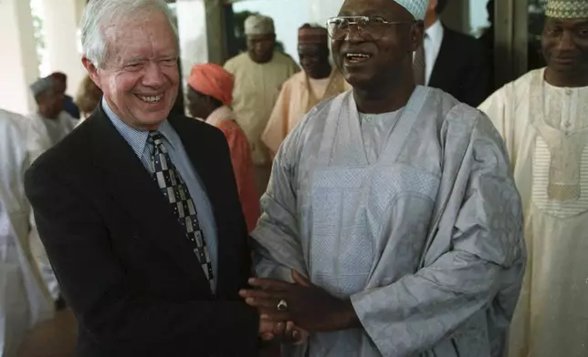 FILE - Nigerian head of state Gen. Abdulsalami Abubakar shakes hands with former U.S. President Jimmy Carter after a meeting at the Nigerian Presidential Villa in the capital Abuja, on Feb. 28, 1999. (AP Photo/Danny Wilcox Frazier, File)