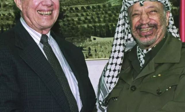 FILE - PLO chairman Yasser Arafat shakes hands with former President Jimmy Carter before their meeting at Arafat's office in Gaza City, on the eve of the first Palestinian elections, Jan. 19, 1996. (AP Photo/Adel Hana, File)