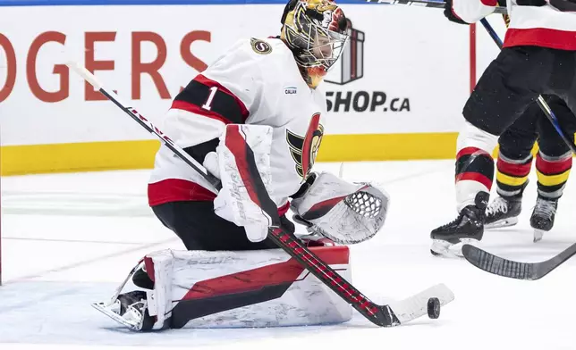 Ottawa Senators goaltender Leevi Merilainen (1) stops the puck against the Vancouver Canucks during the third period of an NHL hockey game in Vancouver, British Columbia, Saturday, Dec. 21, 2024. (Ethan Cairns/The Canadian Press via AP)