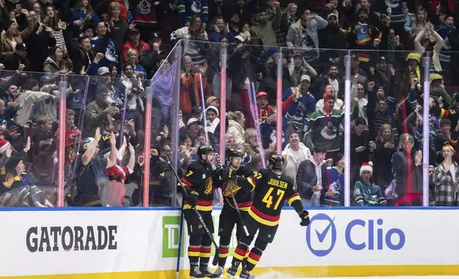 Vancouver Canucks' Elias Pettersson, center, celebrates after his goal with Carson Soucy (7) and Noah Juulsen (47) during second-period NHL hockey game action against the San Jose Sharks in Vancouver, British Columbia, Monday, Dec. 23, 2024. (Ethan Cairns/The Canadian Press via AP)