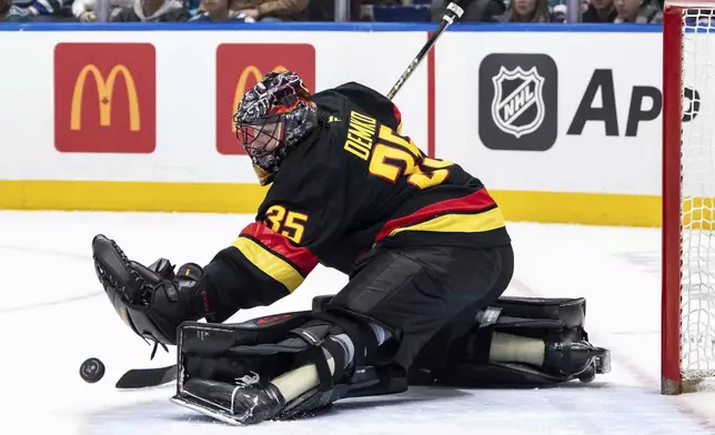 Vancouver Canucks goaltender Thatcher Demko (35) stops the puck against the San Jose Sharks during first-period NHL hockey game action in Vancouver, British Columbia, Monday, Dec. 23, 2024. (Ethan Cairns/The Canadian Press via AP)