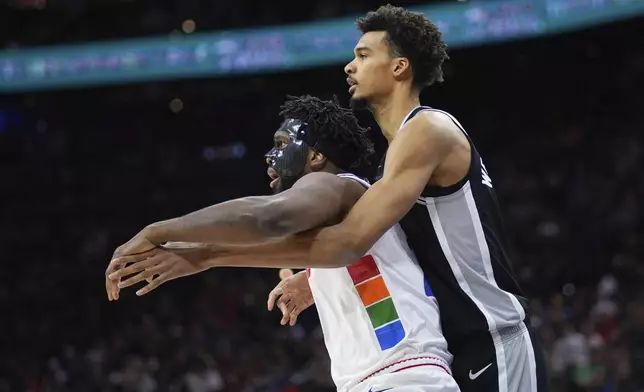 Philadelphia 76ers' Joel Embiid, left, and San Antonio Spurs' Victor Wembanyama battle for postinon during the first half of an NBA basketball game, Monday, Dec. 23, 2024, in Philadelphia. (AP Photo/Matt Slocum)