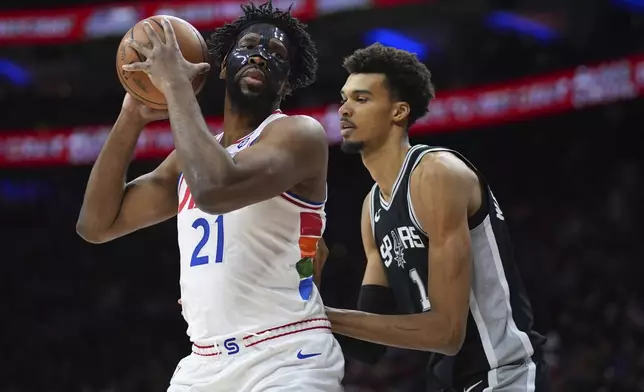 Philadelphia 76ers' Joel Embiid, left, tries to get around San Antonio Spurs' Victor Wembanyama during the first half of an NBA basketball game, Monday, Dec. 23, 2024, in Philadelphia. (AP Photo/Matt Slocum)