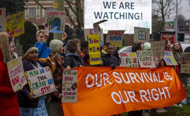 Activists protest outside the International Court of Justice, in The Hague, Netherlands, as it opens hearings into what countries worldwide are legally required to do to combat climate change and help vulnerable nations fight its devastating impact, Monday, Dec. 2, 2024. (AP Photo/Peter Dejong)