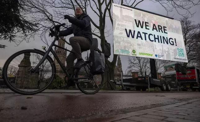 Activists put up a billboard outside the International Court of Justice, in The Hague, Netherlands, as it opens hearings into what countries worldwide are legally required to do to combat climate change and help vulnerable nations fight its devastating impact, Monday, Dec. 2, 2024. (AP Photo/Peter Dejong)