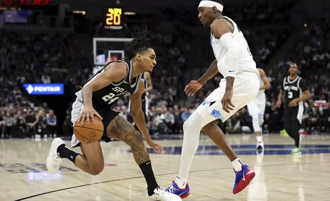 San Antonio Spurs guard Devin Vassell, left, works toward the basket as Minnesota Timberwolves forward Jaden McDaniels defends during the first half of an NBA basketball game Sunday, Dec. 29, 2024, in Minneapolis. (AP Photo/Matt Krohn)