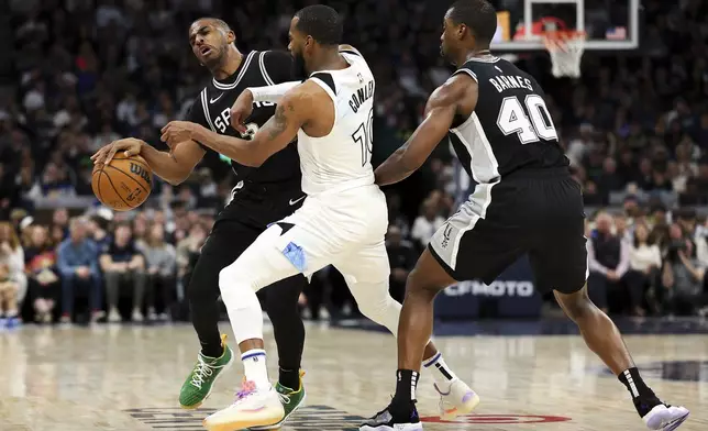 Minnesota Timberwolves guard Mike Conley, middle, fouls San Antonio Spurs guard Chris Paul, left, during the first half of an NBA basketball game Sunday, Dec. 29, 2024, in Minneapolis. (AP Photo/Matt Krohn)